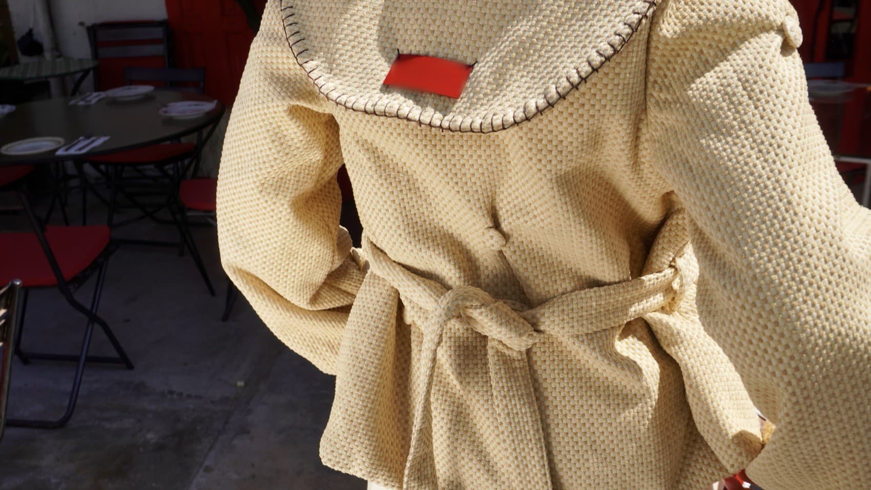 Detalle de la chaqueta de punto: cuello con pespunte a mano y cinturón anudado